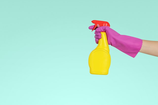 A hand with a glove holding a spray bottle