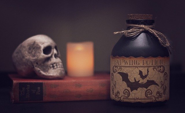 A skull, a lit candle, a potion, and a book.