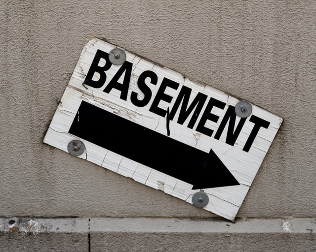 A white wooden sign with basement written on it