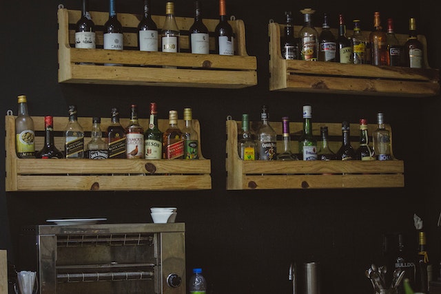 Wall-mounted shelves holding liquor bottles in the kitchen.