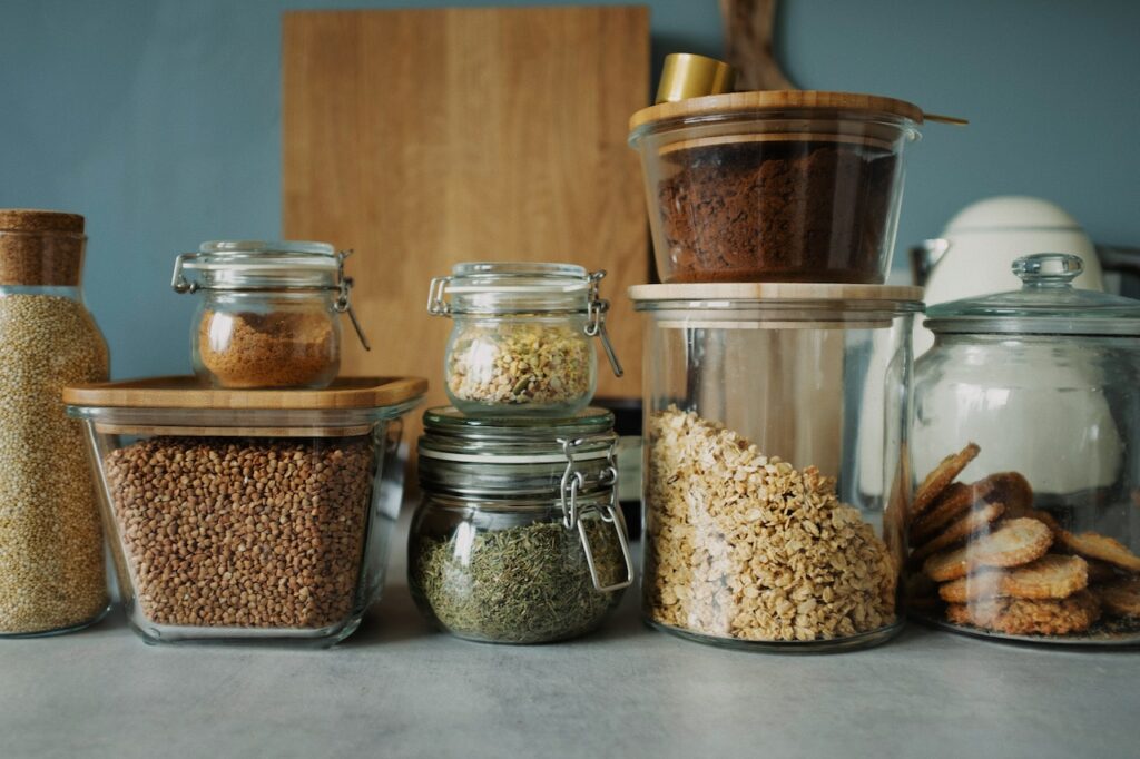 Several clear jars and boxes with lids which are great to use in order to create more storage in your pantry.
