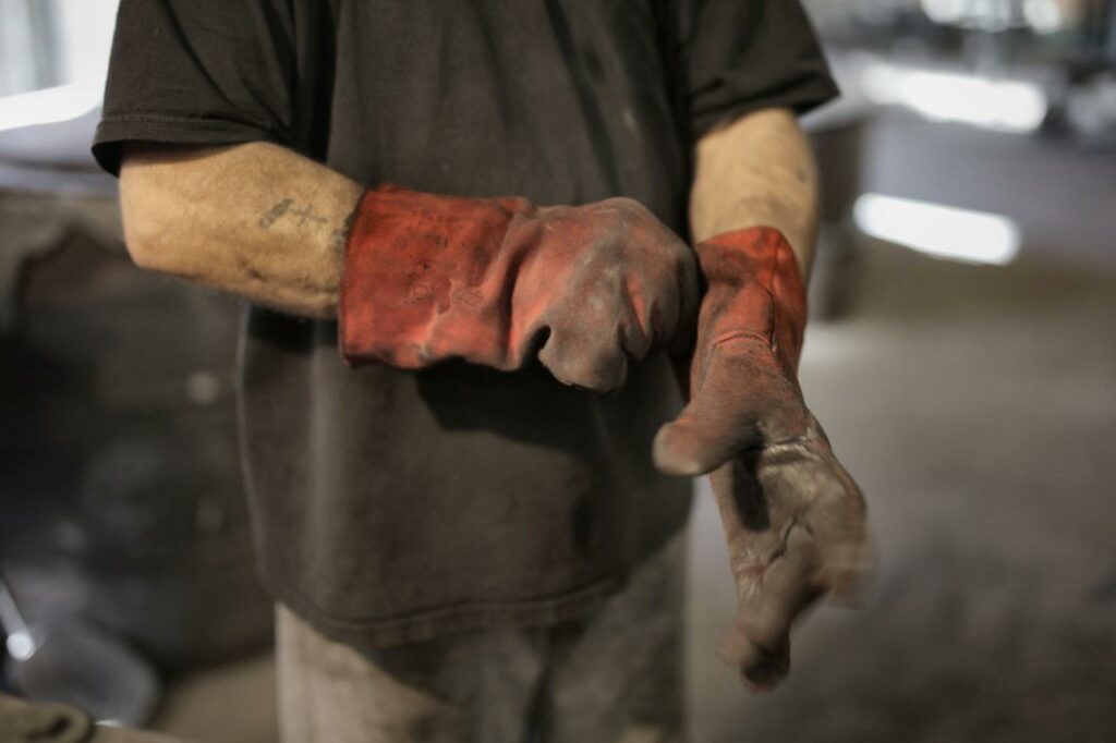 A man wearing heavy-duty gloves and some dirty clothes