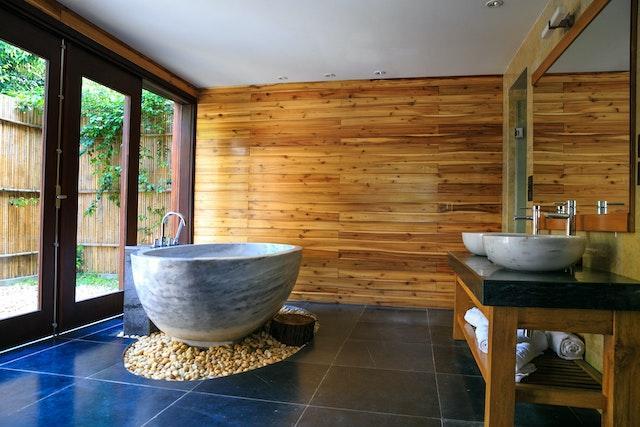 A bathroom with wooden walls and a stone bathtub.