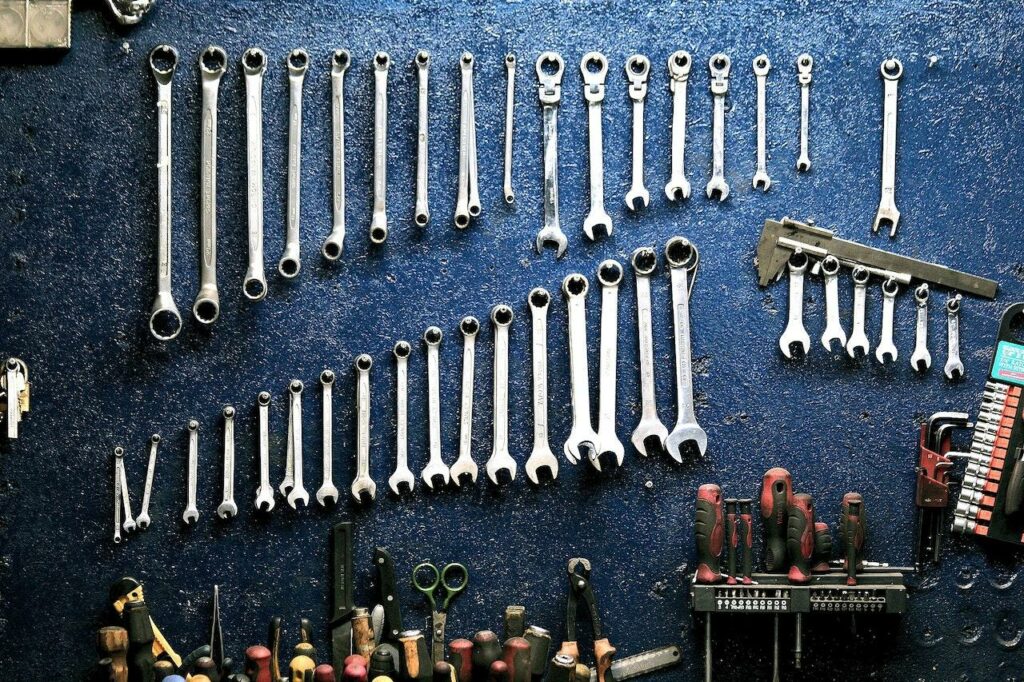 A set of tools hangs on a dark wall.