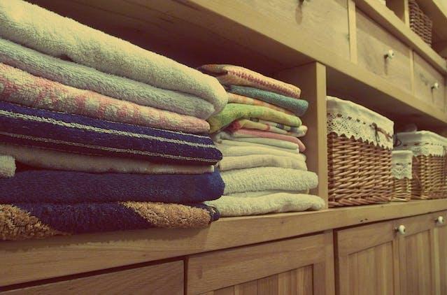 Colorful towels on a brown, wooden shelve