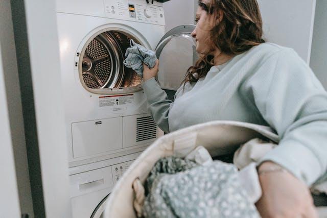 A woman putting laundry in a washing machine