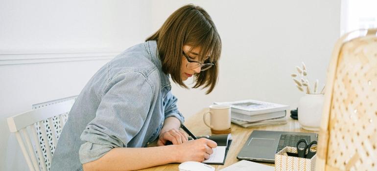 A woman writing at a desk in a home office